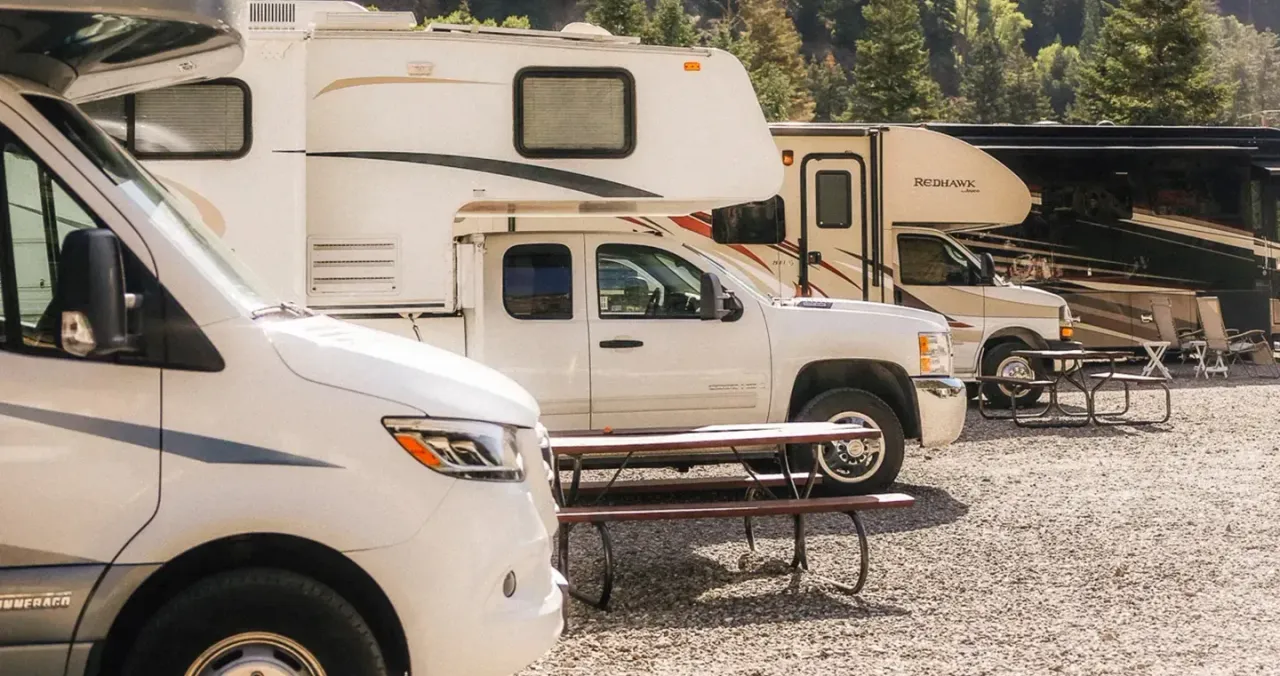 4 parked RVs on a gravel base at a campground