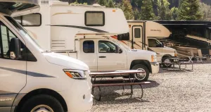 4 parked RVs on a gravel base at a campground