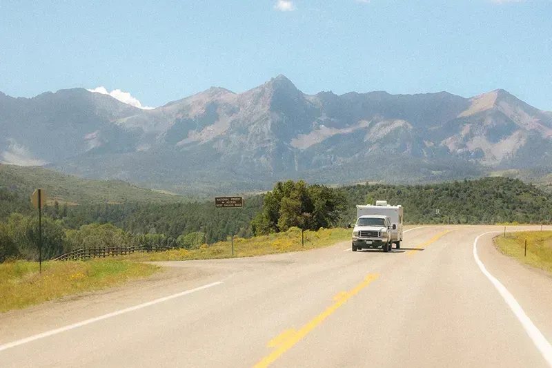 RV driving down a road with mountains in the background