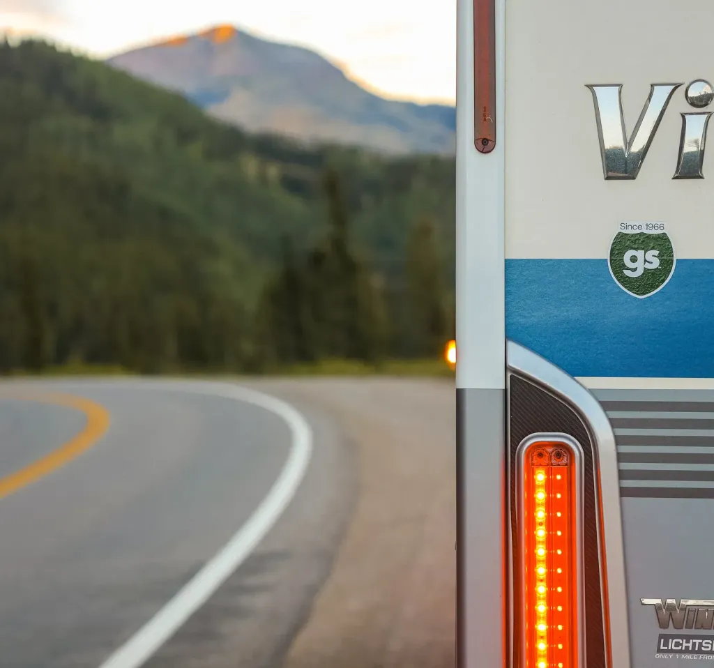 Close up image of an RV tail light on the side of the road with mountains ahead.