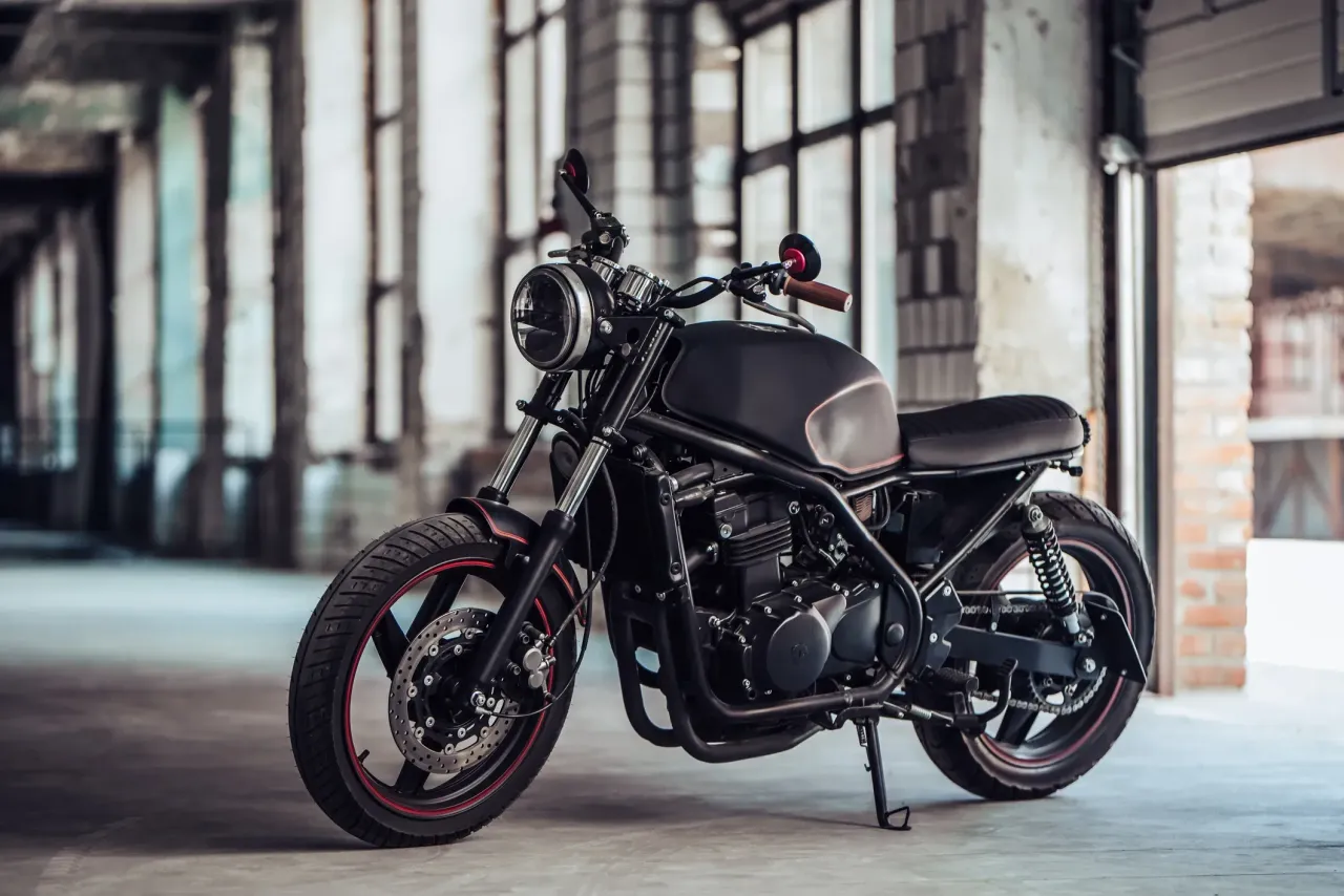 A black cruiser motorcycle in a garage full of windows.  